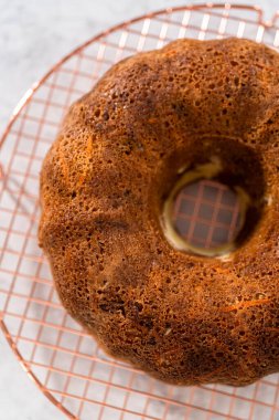 Soğutucu rafı yuvarlamak için taze fırınlanmış havuçlu keki kek kalıbından kaldırıyorum..