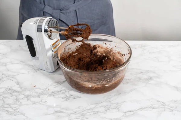 Mixing ingredients with a hand mixer to bake chocolate cookies with chocolate hearts for Valentines Day.