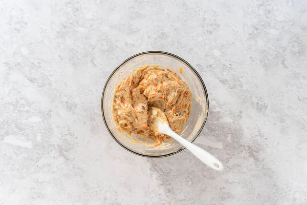 stock image Flat lay. Mixing wet and dry ingredients with a hand whisk in a glass mixing bowl to bake a carrot bundt cake with cream cheese frosting.