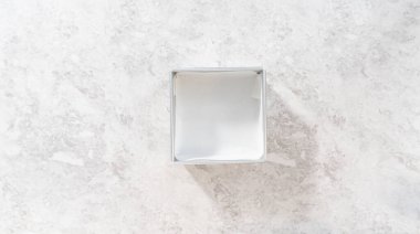 Düz yatıyordu. Çubuk şekerleme hazırlamak için kare peynirli kek tepsisini parşömen kağıdıyla kaplamak.