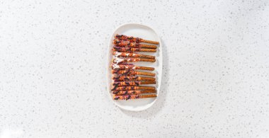 Düz yatıyordu. Cadılar Bayramı çikolata kaplı çubuk çubuklar beyaz servis tabağına serpiştirilmiş.