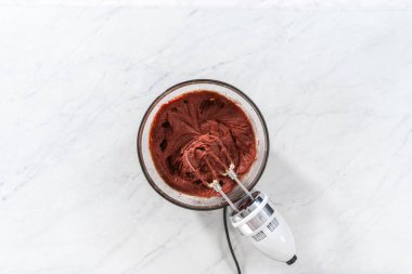 Düz yatıyordu. Kırmızı kadife kek ve krem peynir jöleli kek yapmak için büyük bir bardakta karıştırma malzemesi..