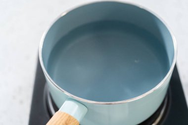 Çikolata parçacıkları ve diğer malzemeleri kaynayan suyun üzerine karıştırıp kabak aromalı şekerleme hazırlıyorum..