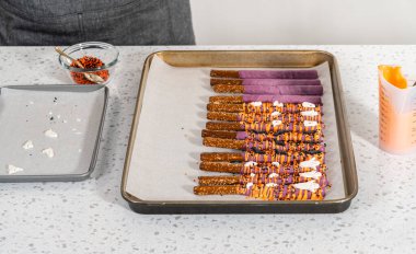 Çubuk krakerleri erimiş çikolataya batırıp Cadılar Bayramı 'nda çikolata kaplı çubuk kraker yapmak..