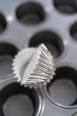Scooping cupcake batter with dough scoop into a baking pan with liners to bake American flag mini cupcakes.