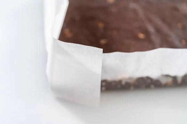 从铺有羊皮纸的方块芝士蛋糕平底锅中取出巧克力坚果软糖 — 图库照片