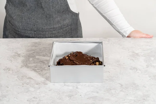 Αφαιρούμε Σοκολατένια Macadamia Fudge Από Ένα Τετράγωνο Cheesecake Τηγάνι Λαδόκολλα — Φωτογραφία Αρχείου