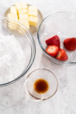 Çilekli tereyağlı kremayı hazırlamak için bardaktaki karışımlar..