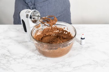 Büyük bir bardakta ıslak malzemeler karıştırarak kırmızı kadife kekler ve beyaz çikolatalı ganache kreması pişiriyorum..