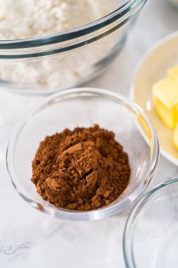 Bardaktaki ölçülü malzemeler karıştırma kaseleri kırmızı kadife kekler ve beyaz çikolatalı ganache kreması..