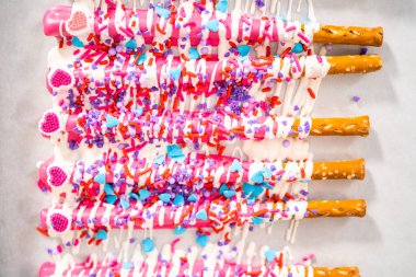 Çikolata soslu çubuk krakerlerin üzerine erimiş çikolata serpiştirmek ve Sevgililer Günü 'nde çikolata kaplı çubuk çubuklar yapmak için çikolata serpiştirmek..