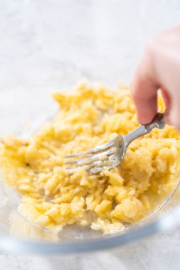 Hindistan cevizli muzlu krep hazırlamak için kırık muzları cam bir kasede kırıyorlar..