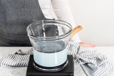 Çikolata parçacıkları ve diğer malzemeleri kaynayan suyun üzerinde karıştırarak çikolatalı şekerleme ve fıstık ezmesi karışımı hazırlıyorum..