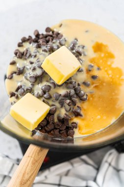 Melting white chocolate chips and other ingredients in the double boiler to prepare chocolate pistachio fudge.