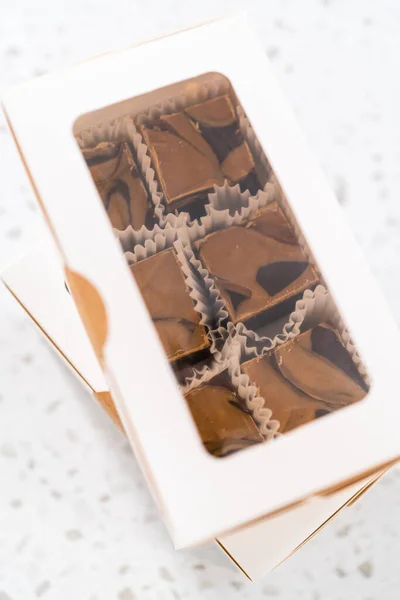 将自制巧克力软糖和花生酱旋入一个白色礼品盒 — 图库照片