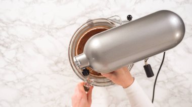 Düz yatıyordu. Adım adım. Elektrikli mutfak mikseriyle çikolatalı ganache çırpmak..