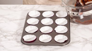 Step by step. Baking chocolate cupcakes. Scooping chocolate cupcake batter into a cupcake pan.