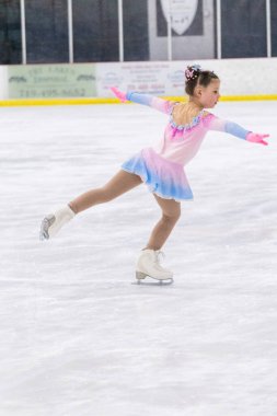 Küçük kız buz pateni pistinde artistik patinaj yapıyor..