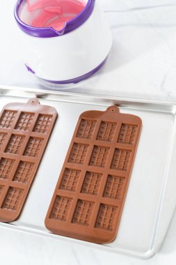 Mini pembe çikolatalar yapmak için silikon çikolata kalıbını erimiş çikolatayla dolduruyorum..