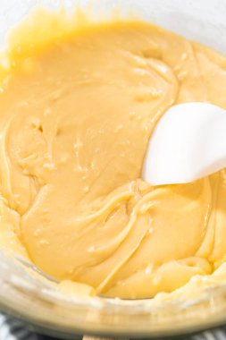 Eriyen beyaz çikolata parçacıkları ve diğer malzemeler kaynamış suyun üzerinde karışıp kızılcık fıstıklı şekerleme hazırlıyor..