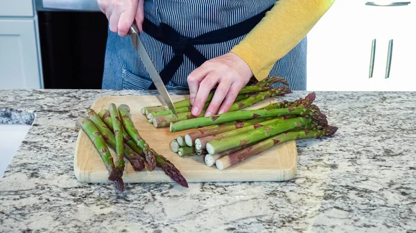 大規模な有機アスパラガスの茎は蒸気の準備で現代の白いキッチンでスライスされています — ストック写真