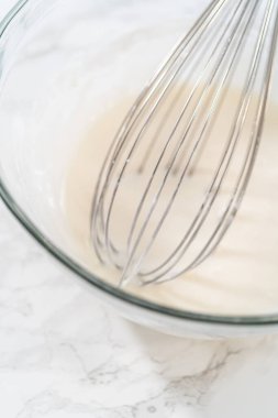 Ev yapımı kraliyet kreması yapmak için büyük bir cam karıştırma kabında malzemeleri karıştırıyorum..