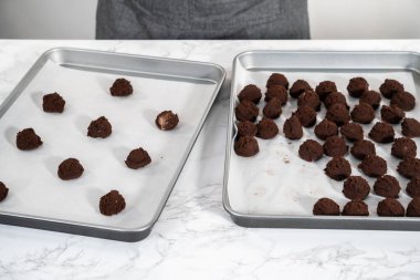 Naneli beyaz çikolatalı kurabiyeler pişirmek için parşömen kağıdıyla kaplı küçük bir hamur kepçesiyle kurabiye hamuru pişirmek..