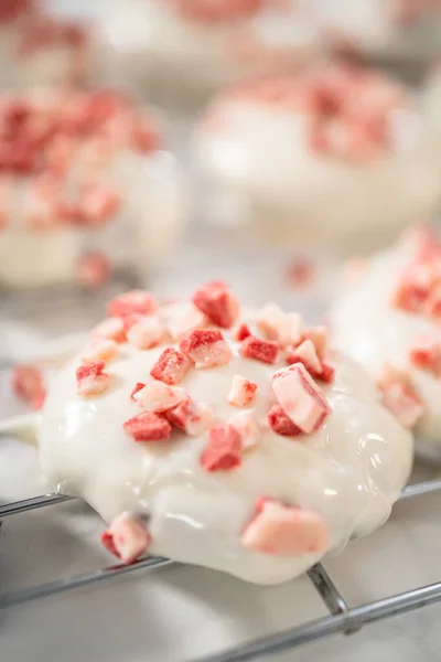 stock image Dipping chocolate cookies into the melted white chocolate to prepare peppermint white chocolate cookies.