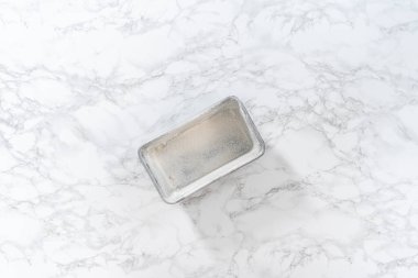 Flat lay. Greasing metal loaf baking pan to bake bread.