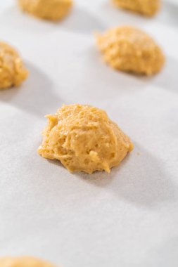 Kurabiye hamuru kepçesiyle kurabiye hamuru pişirip parşömen kağıdıyla kaplanmış bir tepsiye koyup muzlu kurabiyeleri çikolatalı çiselemek..