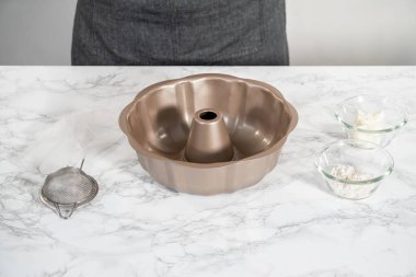 Kadehteki ölçülü malzemeler pişirmek için yağlanmış tavaya karıştırılıyor..