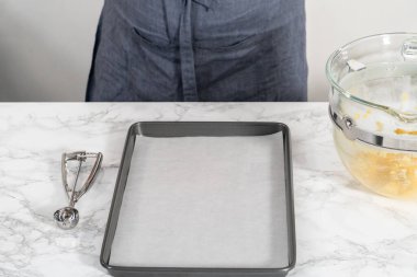 Beyaz çikolatalı limonlu kurabiye. Beyaz çikolatalı limonlu kurabiye pişirmek için parşömen kağıdıyla kaplı bir yemek tepsisine hamur kepçesiyle kurabiye pişirmek..