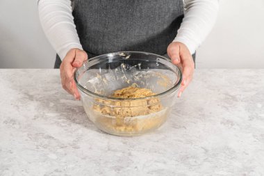 Mixing ingredients with a hand whisk in a large mixing bowl to bake banana cookies with chocolate drizzle.