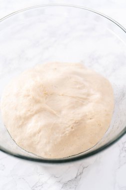 Tarçınlı tatlı pizzası hazırlamak için cam bir kasede pizza hamuru yetiştiriyorum..