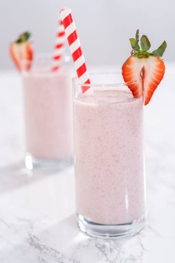 Taze taze çilek ve kağıt kamışla süslenmiş sağlıklı bir kahvaltı muzlu smoothie..