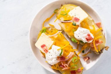 Fırında pişmiş patates. Tereyağı, ekşi krema, peynir ve pastırma parçalarıyla süslenmiş büyük fırında patates..