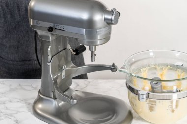 Mixing ingredients in kitchen electric mixer to bake American flag mini cupcakes.