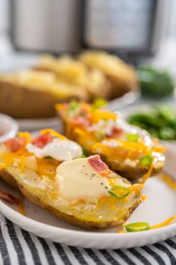 Fırında pişmiş patates. Tereyağı, ekşi krema, peynir ve pastırma parçalarıyla süslenmiş büyük fırında patates..