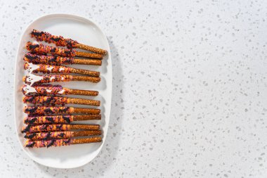 Düz yatıyordu. Cadılar Bayramı çikolata kaplı çubuk çubuklar beyaz servis tabağına serpiştirilmiş.