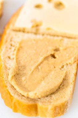 Assembling ham, cucumber, and sprout sandwiches on the white cutting board.