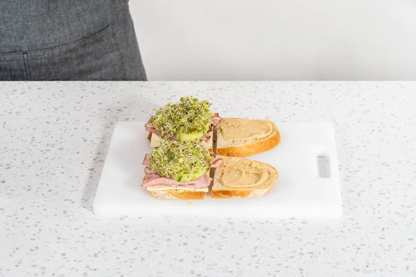 Assembling Ham Cucumber Sprout Sandwiches White Cutting Board — Stok fotoğraf