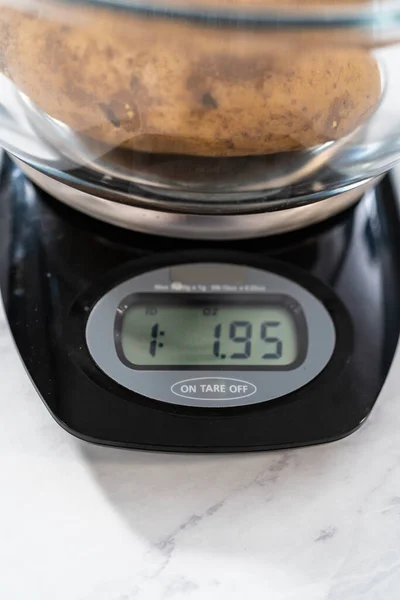 Pressure Cooker Baked Potatoes. Measuring raw potatoes in a glass mixing bowl on the kitchen scale.