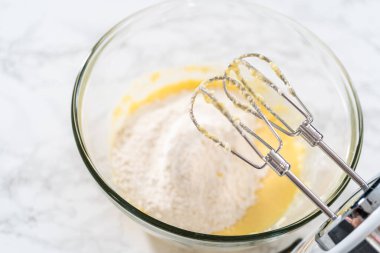 Mini vanilyalı kekler ve ombre pembe kremalı krema pişirmek için büyük bir karıştırma kabında malzemeler karıştırılıyor..