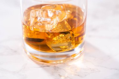Buzlu viski, viski bardağında, beyaz mermer yüzeyde..