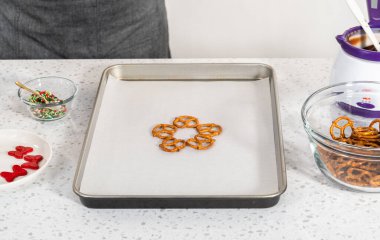 Dipping pretzels twists into melted chocolate to make a chocolate pretzel Christmas wreath.