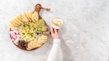 Düz yatıyordu. Sebzeli tereyağı tahtası ve tahta kesme tahtasında ekmek..