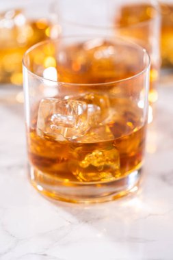 Buzlu viski, viski bardağında, beyaz mermer yüzeyde..