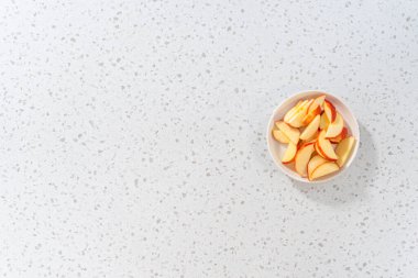 İnce dilimlenmiş kırmızı elmalar beyaz bir tabakta.