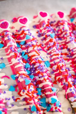 Çikolata soslu çubuk krakerlerin üzerine erimiş çikolata serpiştirmek ve Sevgililer Günü 'nde çikolata kaplı çubuk çubuklar yapmak için çikolata serpiştirmek..