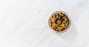 Düz yatıyordu. Soğutulmuş taze pişmiş limonlu yaban mersinli keki soğutucu rafından servis tabağına aktarıyorum..